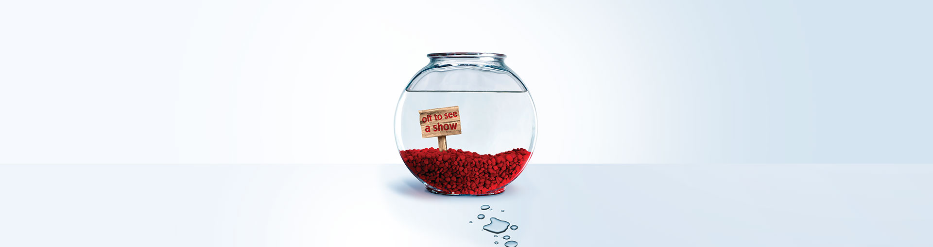 Empty fish bowl with a sign that reads "Off to see a show"