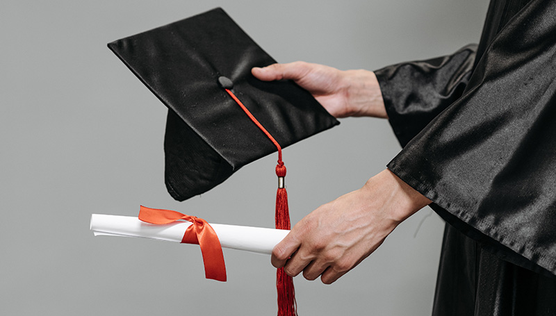 Hands holding graduation cap and diploma
